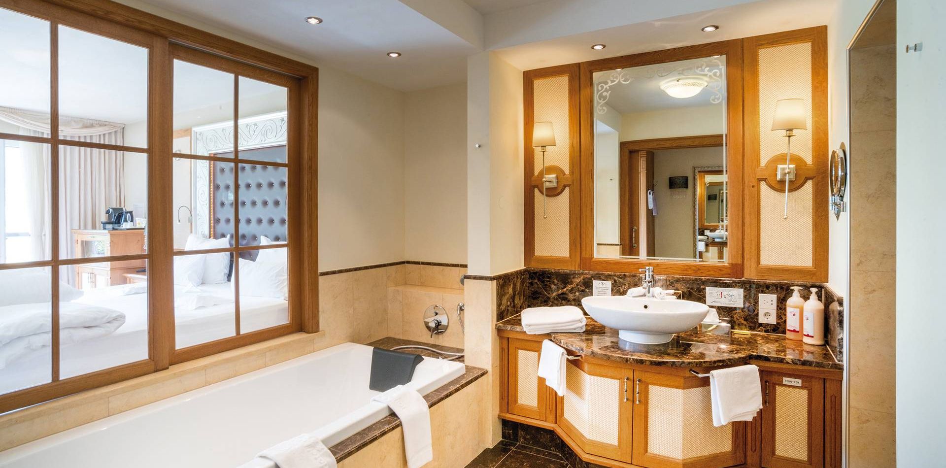 A bathroom with a bathtub, double vanity, and mirror in a luxury suite at Preidlhof.