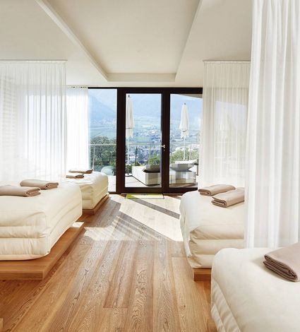 Helle Liegen im Wellnessruheraum mit Blick durch die Glastür auf die Terrasse und das Tal.