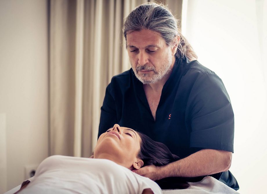 A therapist performs a massage on a woman lying on a treatment bed.