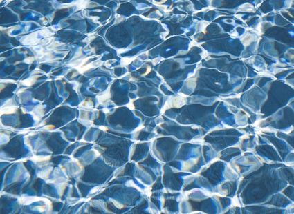 Nahaufnahme von blauem Poolwasser mit bewegten Lichtreflexen und Wellenmustern.