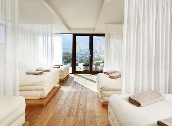 Bright relaxation room with daybeds, sheer curtains and a view toward the mountains.