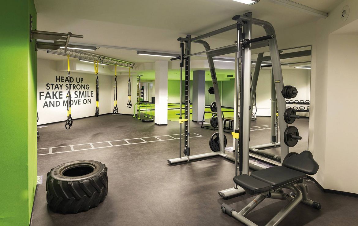 Ein moderner Fitnessraum mit Kraftgeräten, Seilen und einer großen Trainingsreifen im Preidlhof.