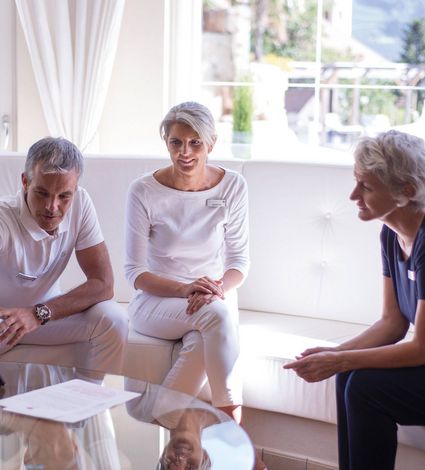 Three people sit together in a bright lounge during a wellness consultation.