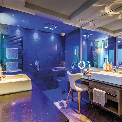 Ein modernes Wellnessbad mit zwei Waschbecken, großer Spiegelwand und blauem Licht im Preidlhof.