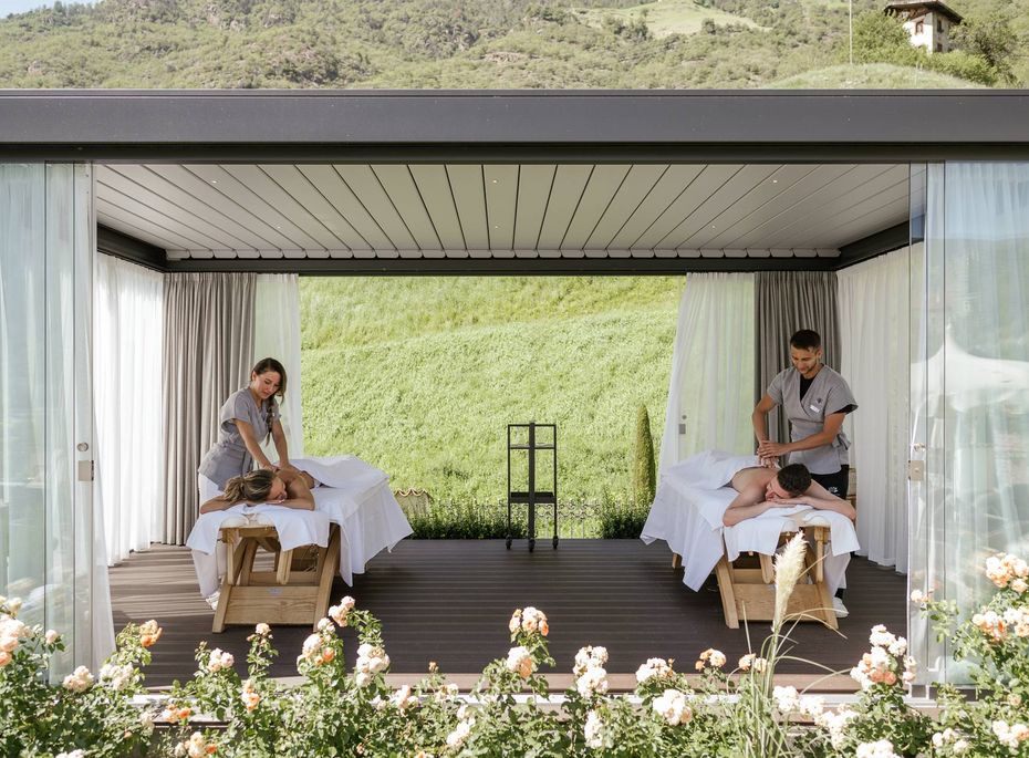 Zwei Wellnessbehandlungen finden in einem offenen Spa-Pavillon mit Blick ins Grüne statt.