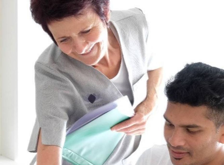 Massagebehandlung im Preidlhof in Naturns Eine Therapeutin beugt sich zu einem Mann und bereitet eine Massagebehandlung vor.