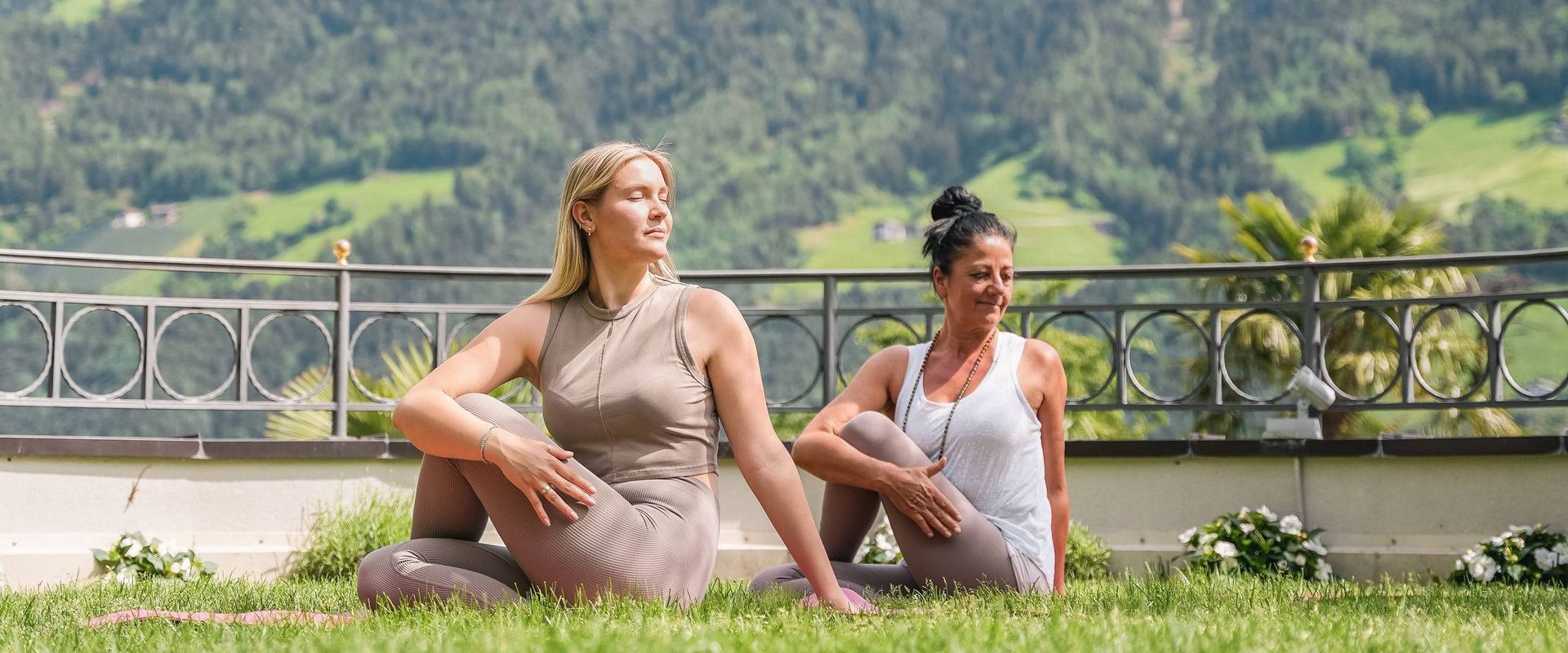 Zwei Frauen machen Yoga im Garten mit Blick auf die Berge bei Preidlhof in Naturns.