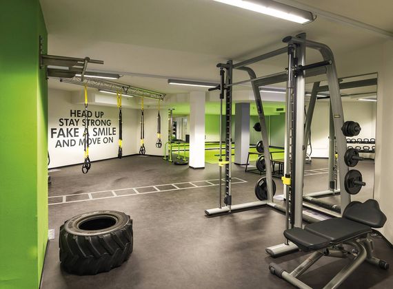 A fitness gym with training machines, suspension straps and exercise equipment inside a bright room.