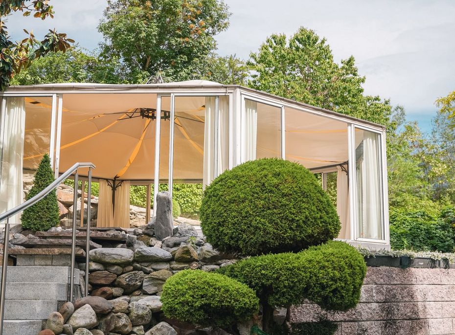 Wellness-Pavillon im Garten des Preidlhof Ein moderner Wellness-Pavillon steht zwischen Felsen und sorgfältig geschnittenen Gartenpflanzen.