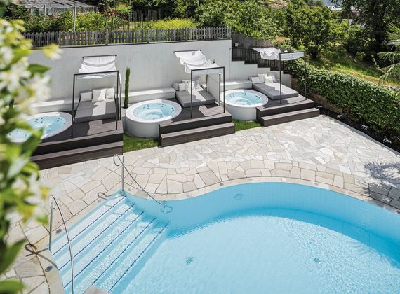 Blick auf die Poollandschaft mit zwei runden Whirlpools, Ruheliegen und einem Außenpool im Preidlhof.