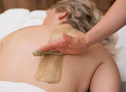 Un'operatrice applica un impacco sulla schiena di una donna durante un trattamento benessere.