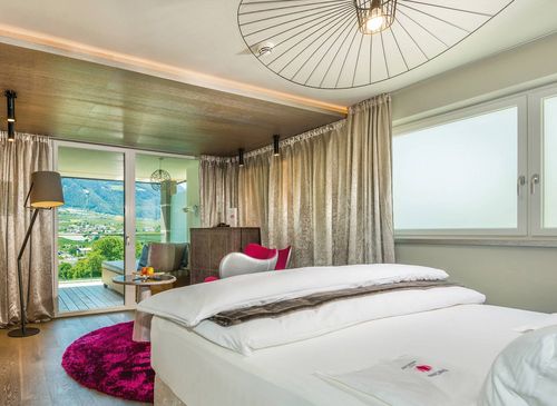 Comfort Room Pink at Preidlhof with mountain view A bright hotel room with twin beds, a balcony door, curtains and a mountain view.