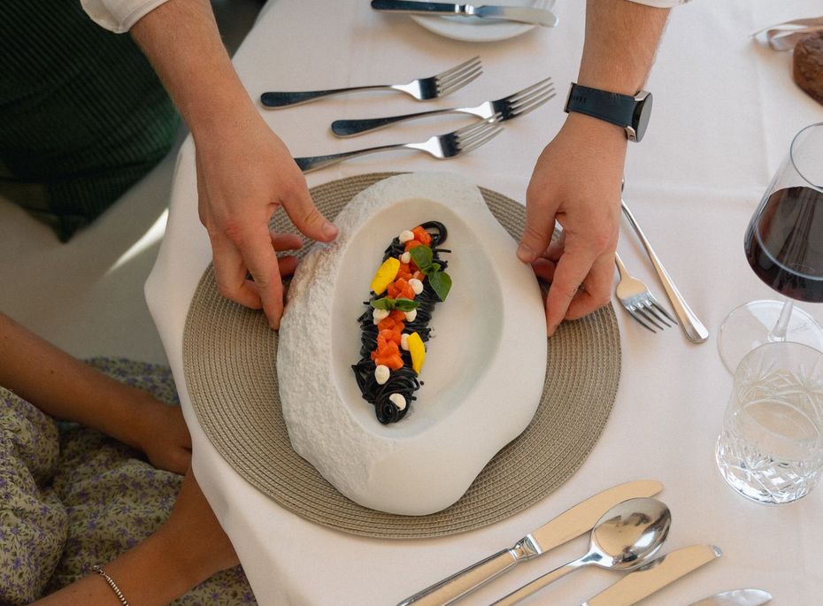 Eine servierte Dessertkomposition wird am Tisch in einem Gourmetrestaurant von zwei Personen platziert.