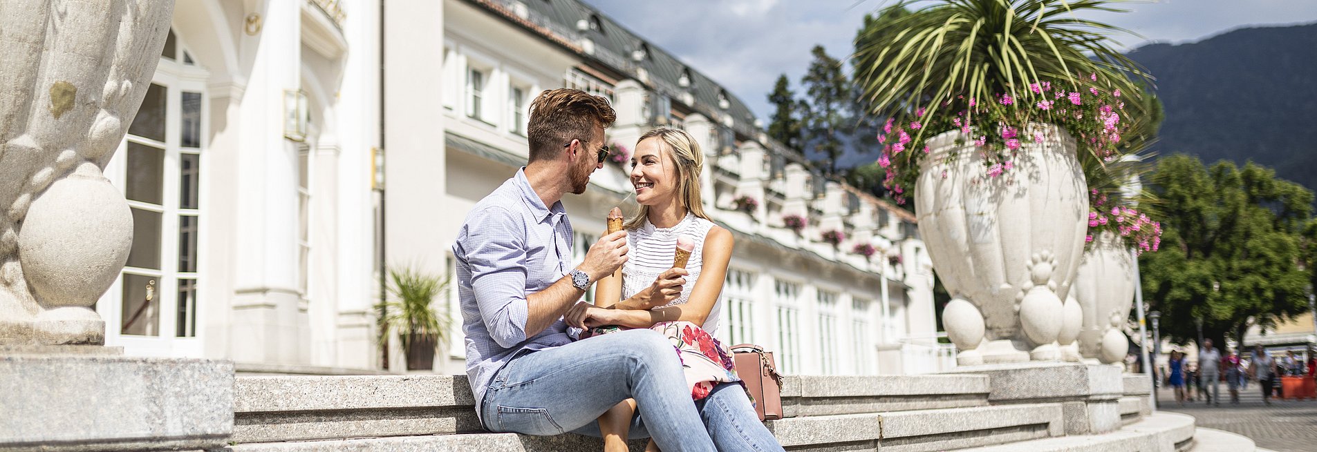 Paar sitzt auf einer Treppe im Freien und isst Eis
