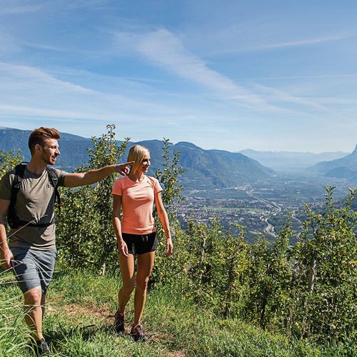 Ein Paar wandert auf einem schmalen Pfad mit Blick ins Tal und auf die Berge oberhalb von Naturns.