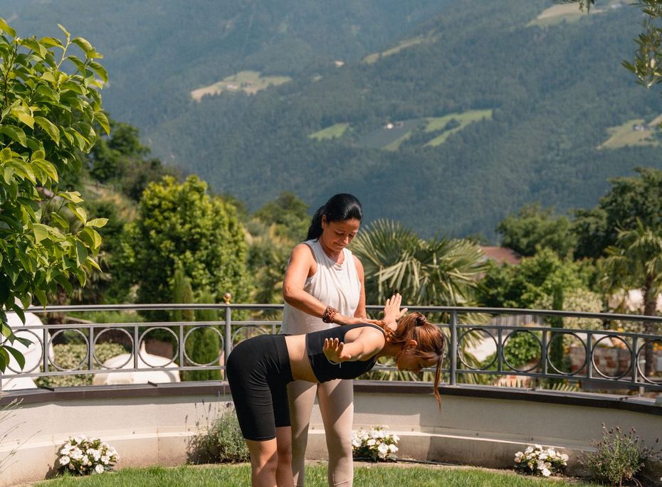 Yoga im Garten des Preidlhof in Naturns Zwei Frauen üben Yoga auf einer Rasenfläche mit Bergblick und Garten im Hintergrund.