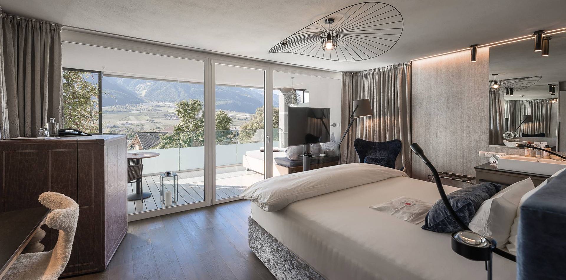 A bright Single Suite Blue with a bed, desk, balcony doors and a mountain view at Preidlhof.
