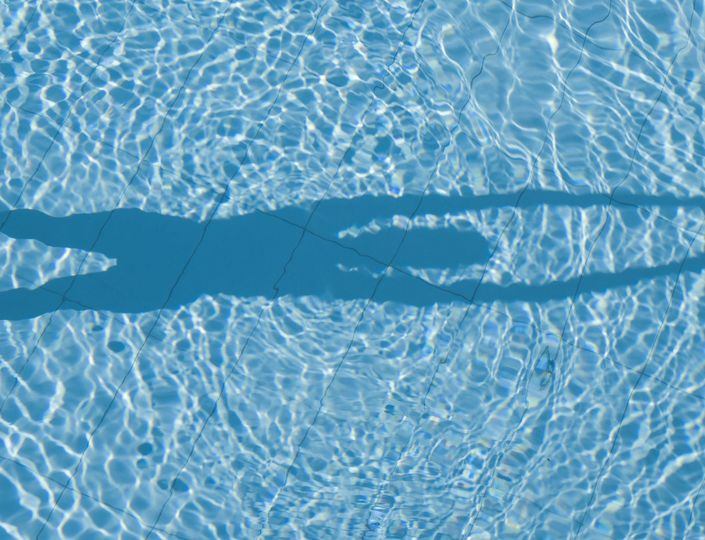 Sunlight creates ripples across the blue water surface of a thermal spa pool.