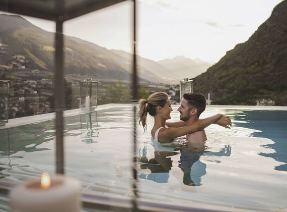 Ein Paar umarmt sich im Infinity-Pool mit Blick auf die Berge.