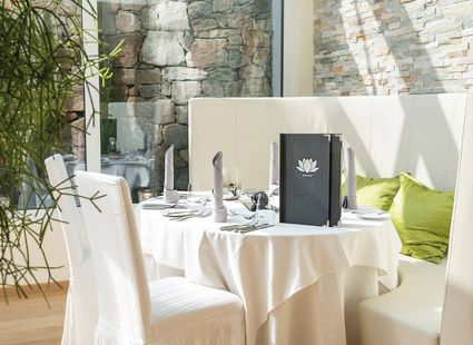 Ein gedeckter Tisch mit weißen Stühlen und grünen Kissen in einer hellen Vinothek.