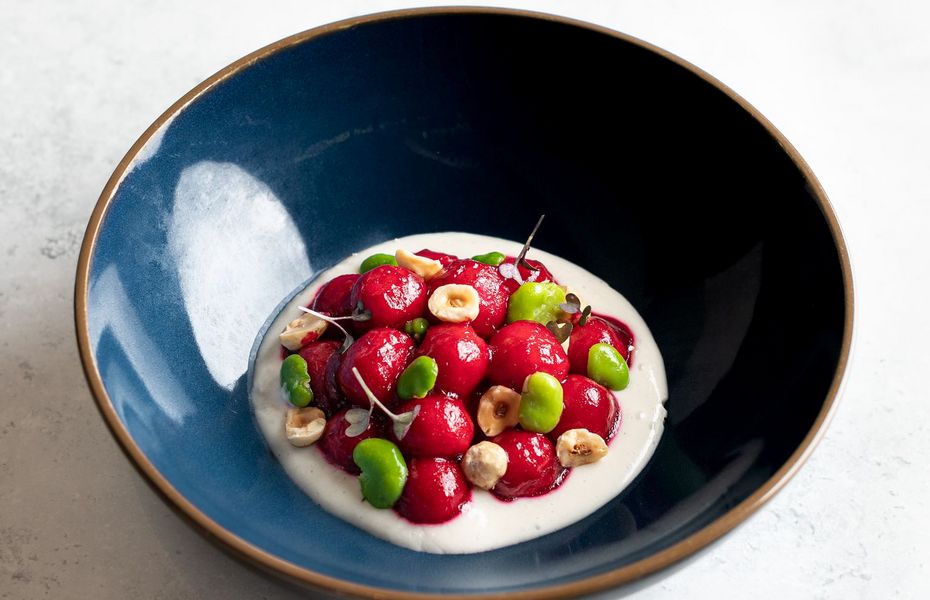 Dessert mit Beeren im Preidlhof Eine Schale mit weißem Dessert, garniert mit roten und grünen Beeren sowie Nüssen auf hellem Untergrund.