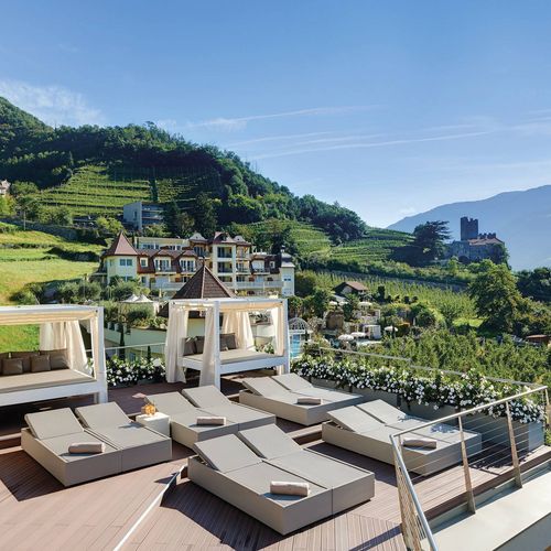 Eine Sonnenterrasse mit Liegen und Blick über die Weinberge und Berge bei einem Wellnesshotel.