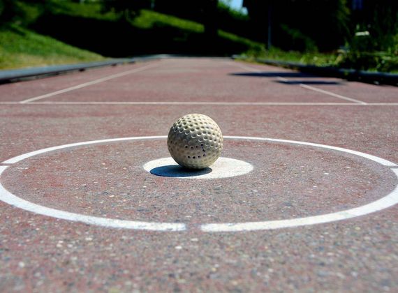 Ein Minigolfball liegt auf dem markierten Feld einer Bahn im Freien.