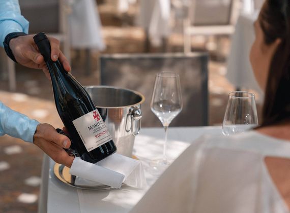 Un membro dello staff versa vino in un calice accanto a un secchiello del ghiaccio e a bicchieri vuoti durante una degustazione al Preidlhof.