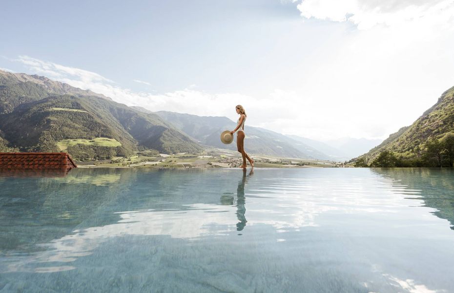 Infinity Pool im Preidlhof mit Bergpanorama Eine Frau steht am Rand eines Infinity-Pools mit Bergpanorama und blickt über das Wasser.