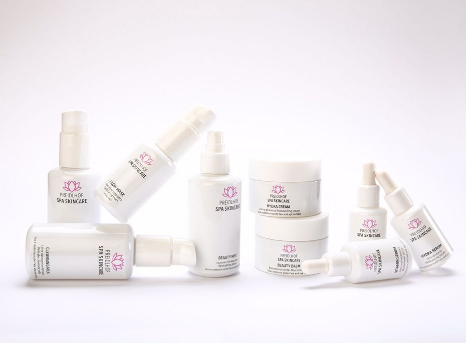 Mehrere weiße Preidlhof Spa Skincare Produkte sind auf hellem Hintergrund arrangiert.