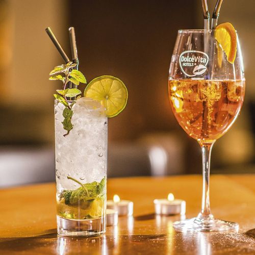 Zwei Cocktails stehen auf einem Tisch an der Bar, im Hintergrund brennen Kerzen und der Raum ist warm beleuchtet.