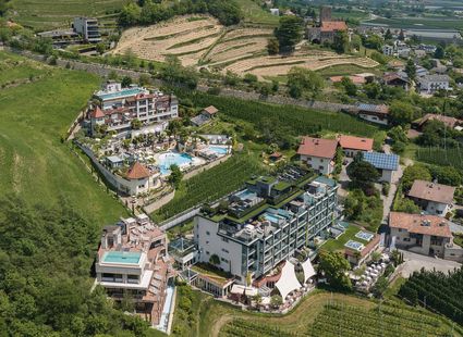Luftaufnahme des Wellnesshotels Preidlhof in Naturns mit Poolanlage und umliegenden Weinbergen.
