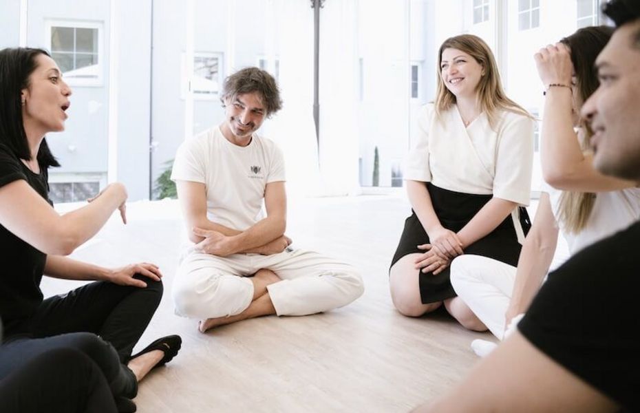 Wellnessgruppe im Preidlhof in Naturns Eine kleine Gruppe sitzt im hellen Raum im Kreis auf dem Boden und spricht miteinander.
