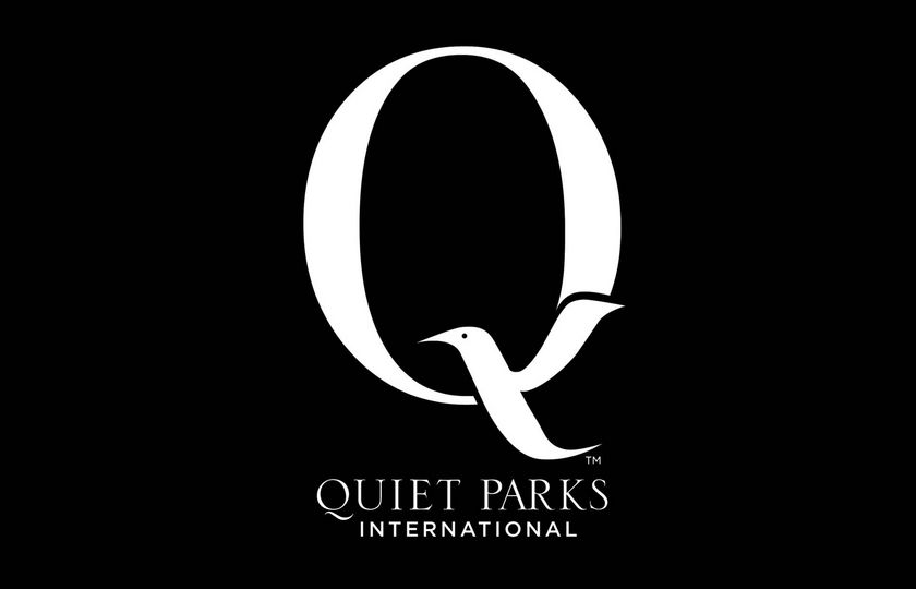 Das Logo von Quiet Parks International auf schwarzem Hintergrund mit großem weißem Q und Vogelmotiv.