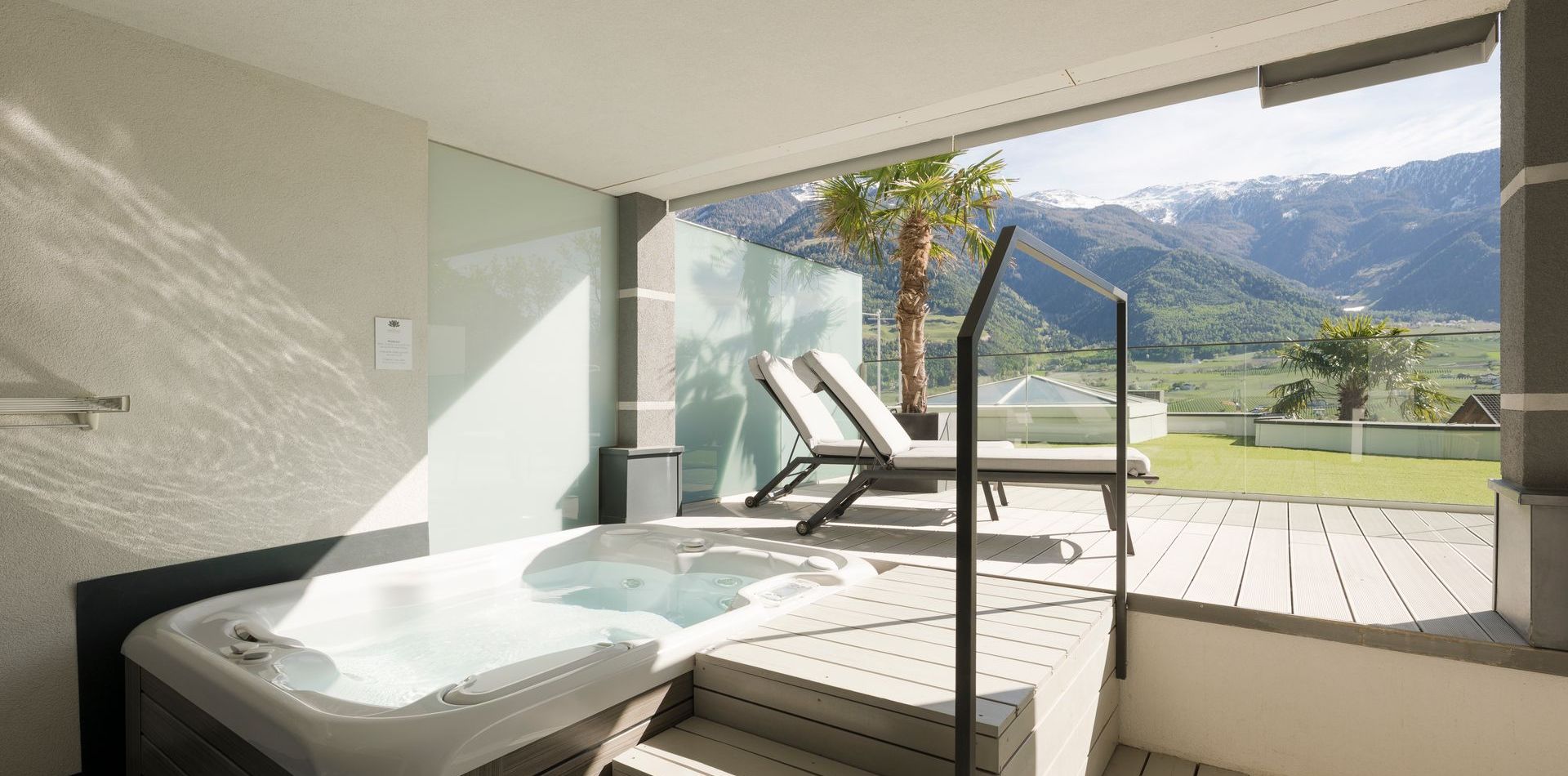Eine private Suite mit Whirlpool und Liegen öffnet sich zu einer Terrasse mit Blick auf Berge und Tal.