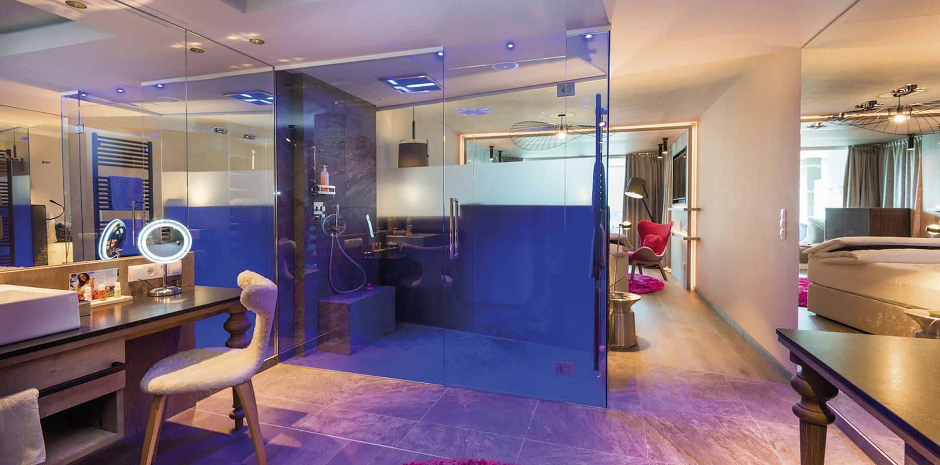 Una suite di lusso con bagno in vetro, vanity, zona salotto e letto al Preidlhof.