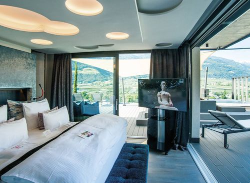 Penthouse Suite with mountain-view terrace A penthouse suite with a large bed, sliding glass doors and a terrace overlooking the mountains.