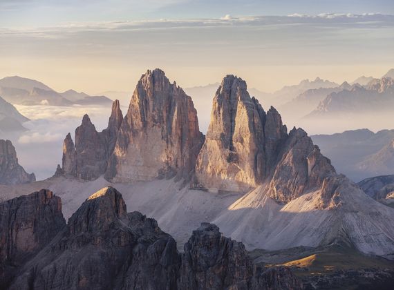 A wide mountain panorama shows dramatic Dolomite peaks lit by soft morning light.