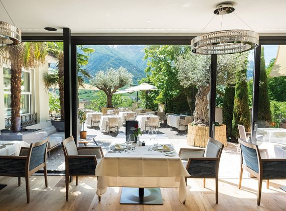 A bright gourmet restaurant dining room with set tables, large windows and mountain views.