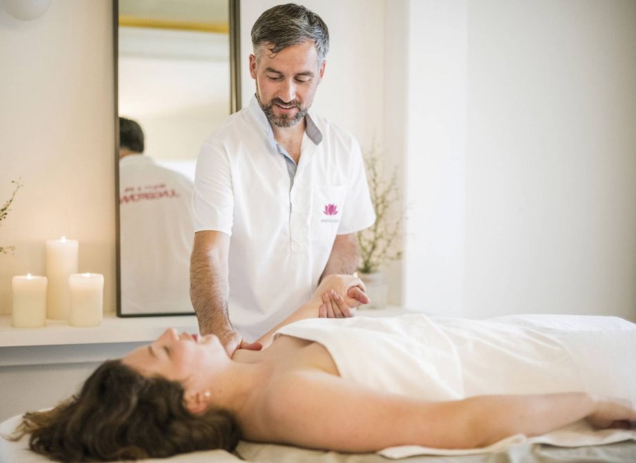 A spa therapist gives a woman a massage on a treatment table in a calm wellness room.