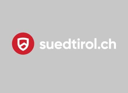 Das Logo von suedtirol.ch steht in Weiß und Rot auf einem grauen Hintergrund.