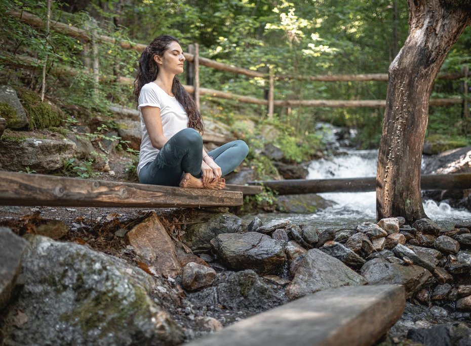 Eine Frau meditiert im Wald.