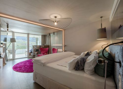 Ein modernes Schlafzimmer in einer Luxury Suite mit Blick ins Grüne und auf die Berge.