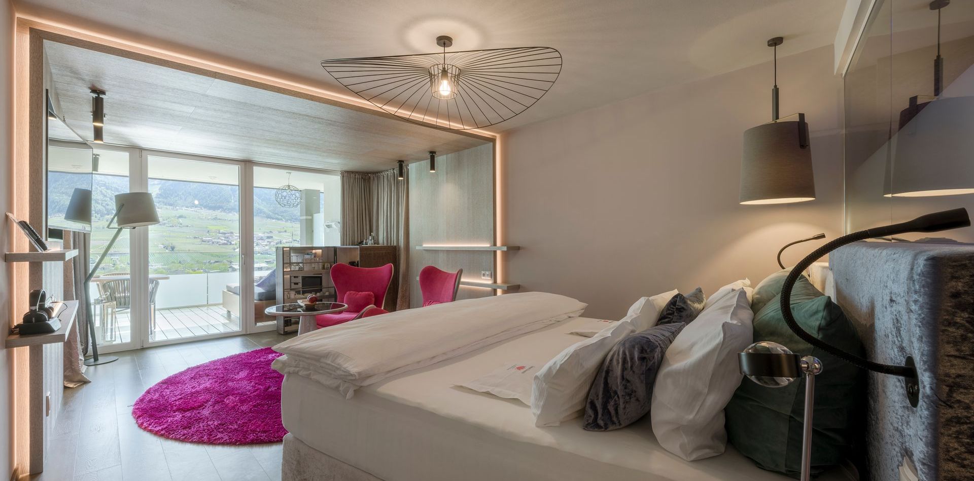 Ein modernes Schlafzimmer in einer Luxury Suite mit Blick ins Grüne und auf die Berge.