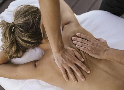 Eine Frau erhält eine Rückenmassage auf einer Liege im Spa-Bereich.