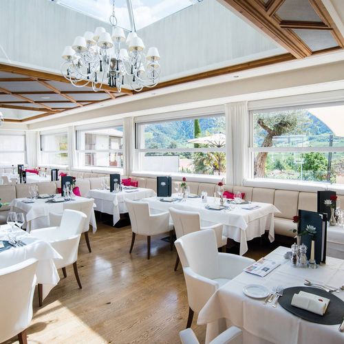 Heller Speisesaal mit eingedeckten Tischen und großen Fenstern mit Blick auf die Berge.