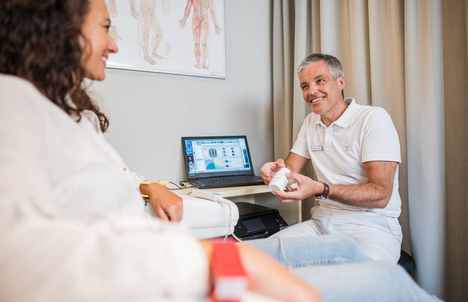 Ein Mann sitzt mit einer Beraterin im Medical Spa und hält ein kleines Produkt in der Hand.
