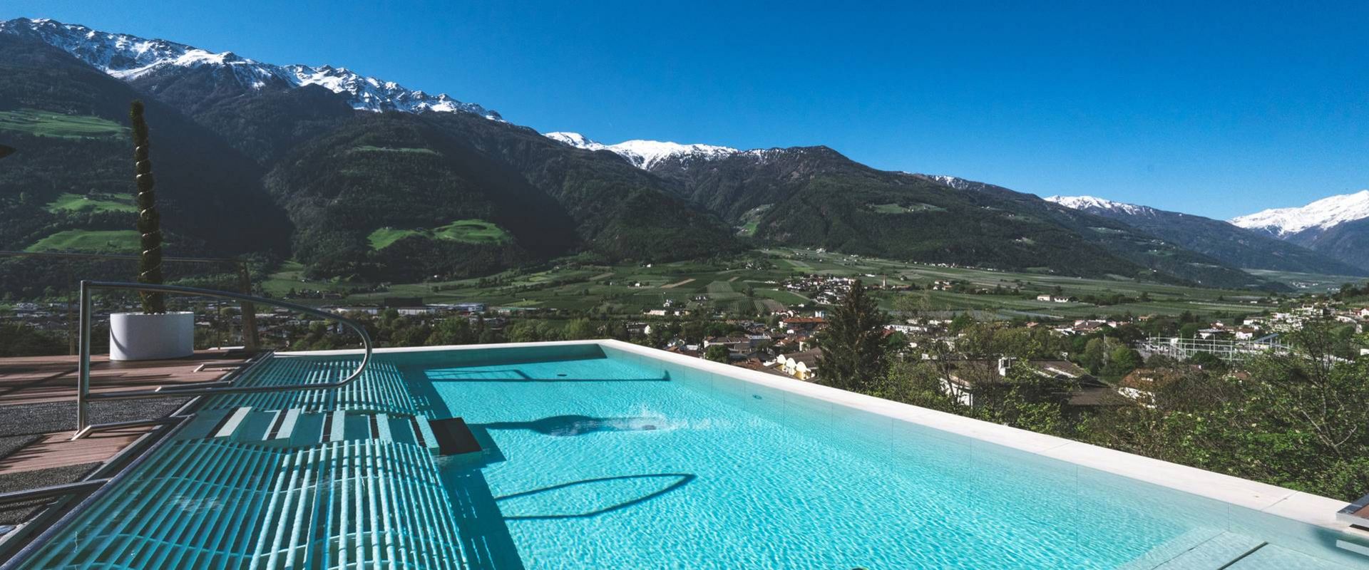 Una piscina a sfioro domina la valle e le montagne sotto un cielo limpido e azzurro.