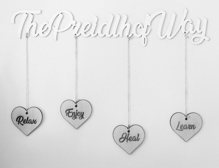 A white wall sign reads The Preidlhof Way above four hanging heart plaques labeled Relax, Enjoy, Heal and Learn.
