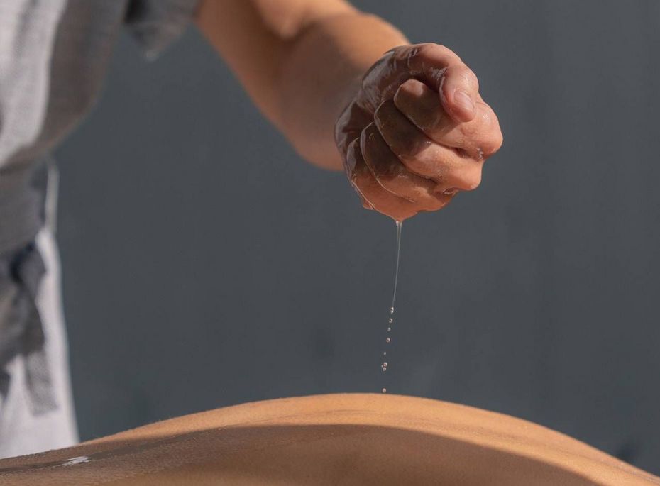 Massage im Preidlhof in Naturns Eine Masseurin tropft Öl auf den Rücken eines Gastes bei einer Massage.